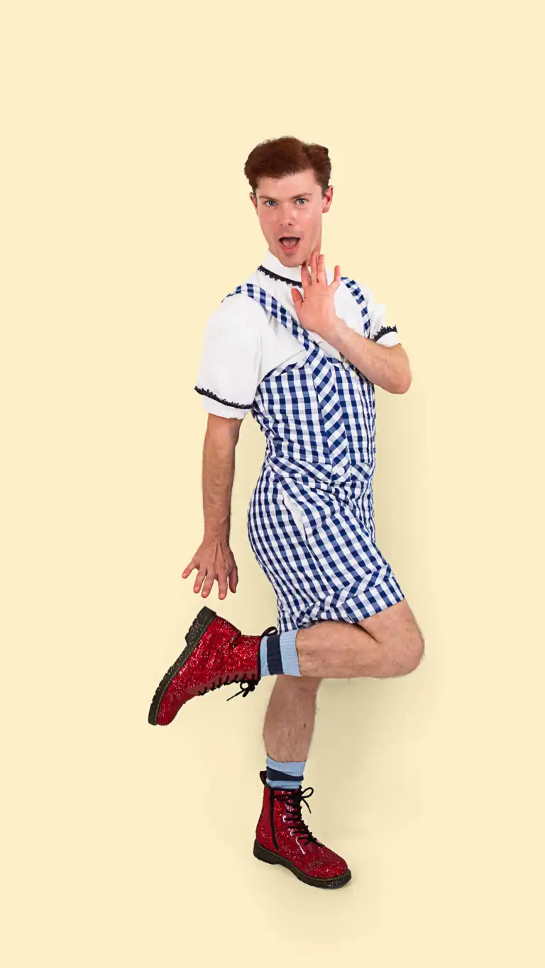 Designs Elijah's Dorothy costume, a gingham shorts jumper with pockets, detailed collar and sleeves, and sparkly red boots.