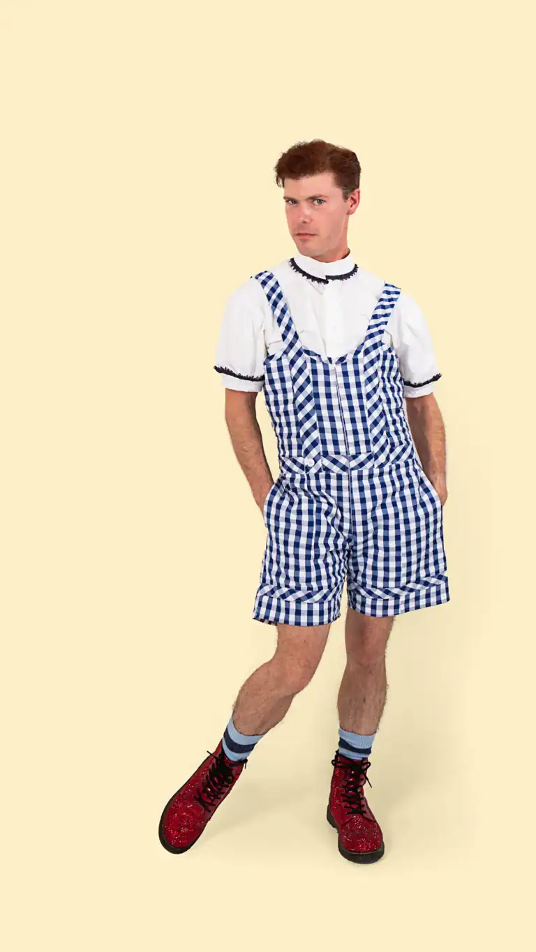 Designs Elijah's Dorothy costume, a gingham shorts jumper with pockets, detailed collar and sleeves, and sparkly red boots.