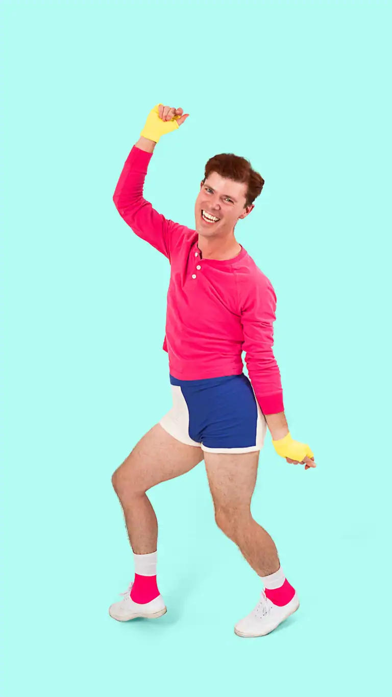 Designs Elijah's George Michael costume, posed mid-dance twist.